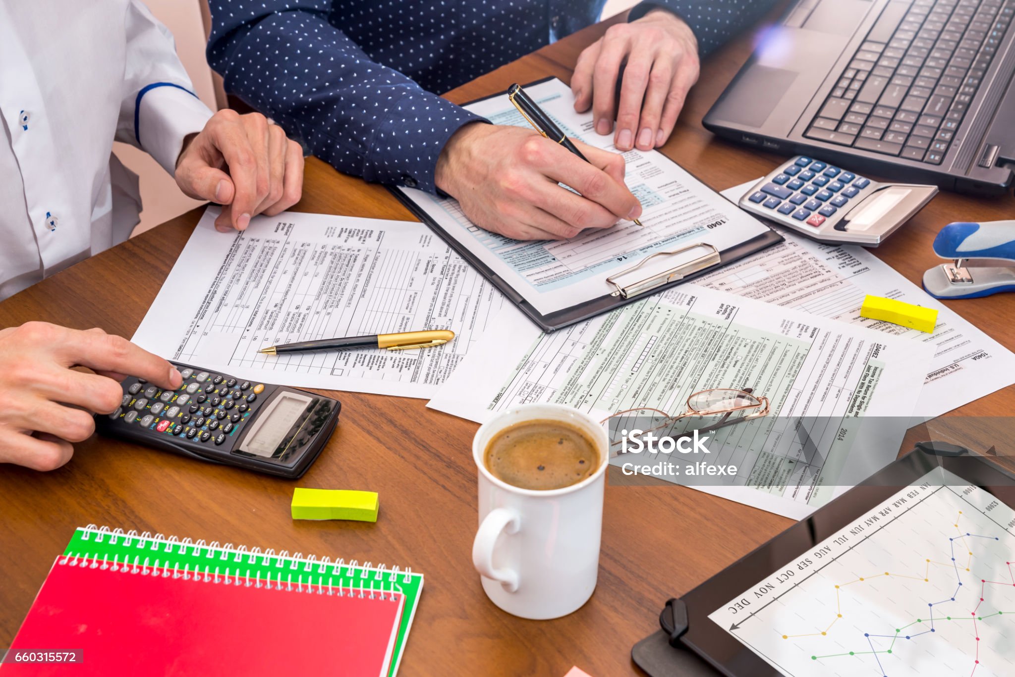 two mens filling USA Tax 1040 Form with calculator, tablet.